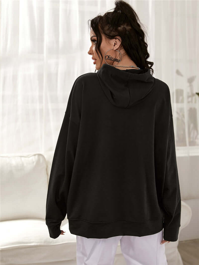 Woman wearing a black printed drop-shoulder hooded sweatshirt, showcasing the back view with a relaxed fit.