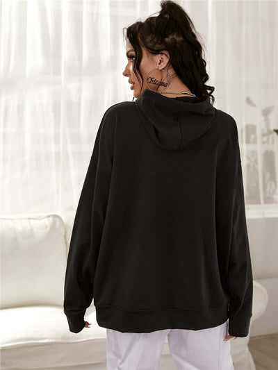Woman wearing a black printed drop-shoulder hooded sweatshirt, showcasing the back view with a relaxed fit.
