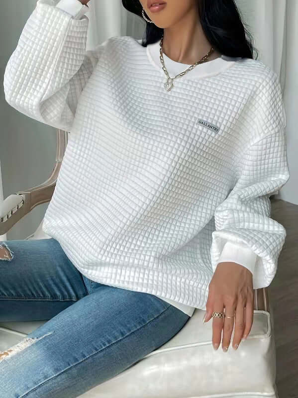 White letter patch drop shoulder sweatshirt paired with jeans, showcasing a loose fit and long sleeves.