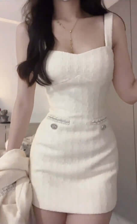 Model wearing a stylish white evening dress with spaghetti straps and decorative buttons.