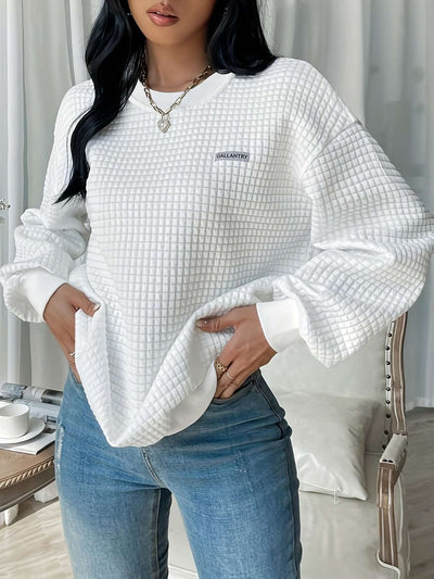 Model wearing a white quilted letter patch drop shoulder sweatshirt, styled with casual blue jeans.
